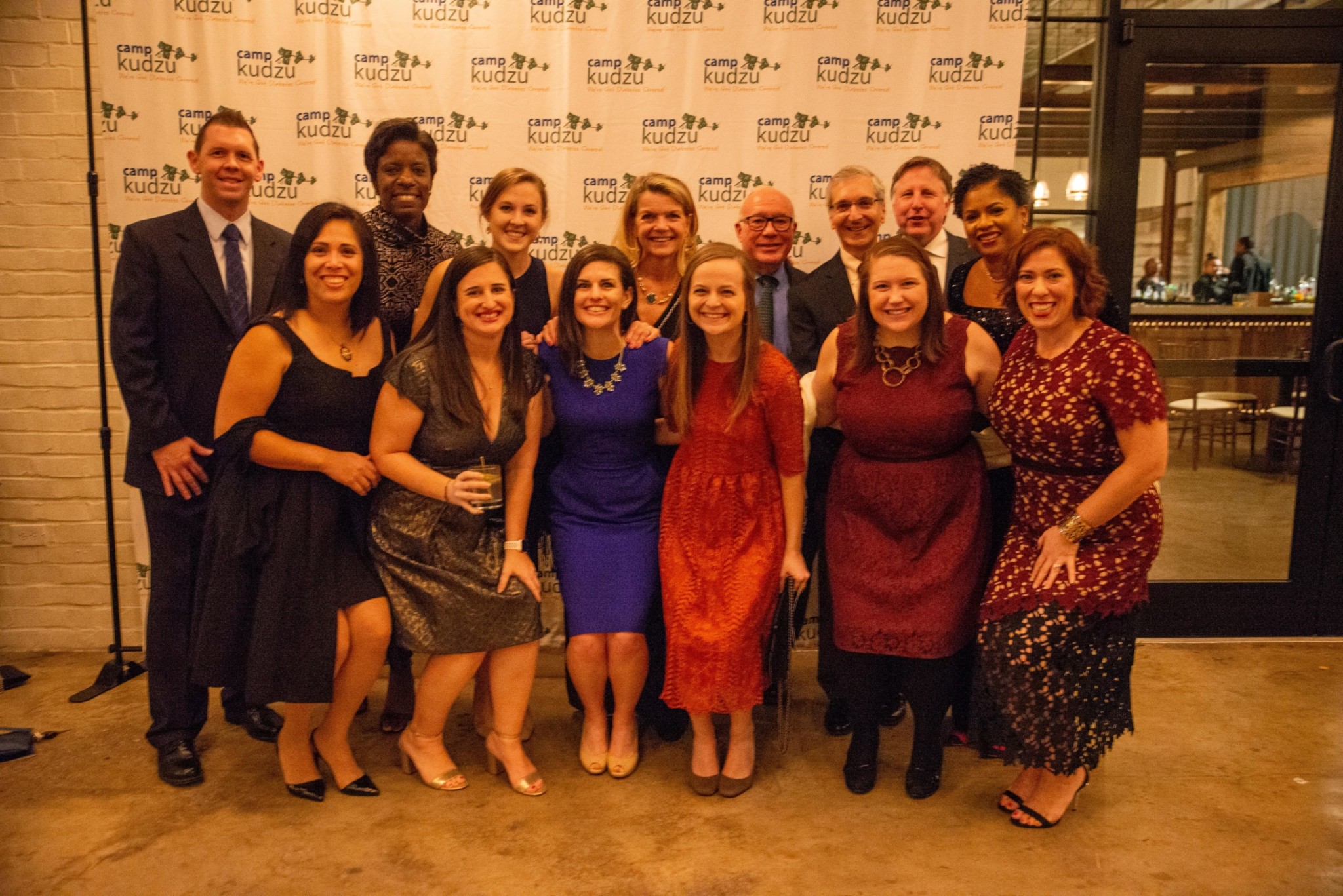 Event attendees posing for a picture in front of a logo background