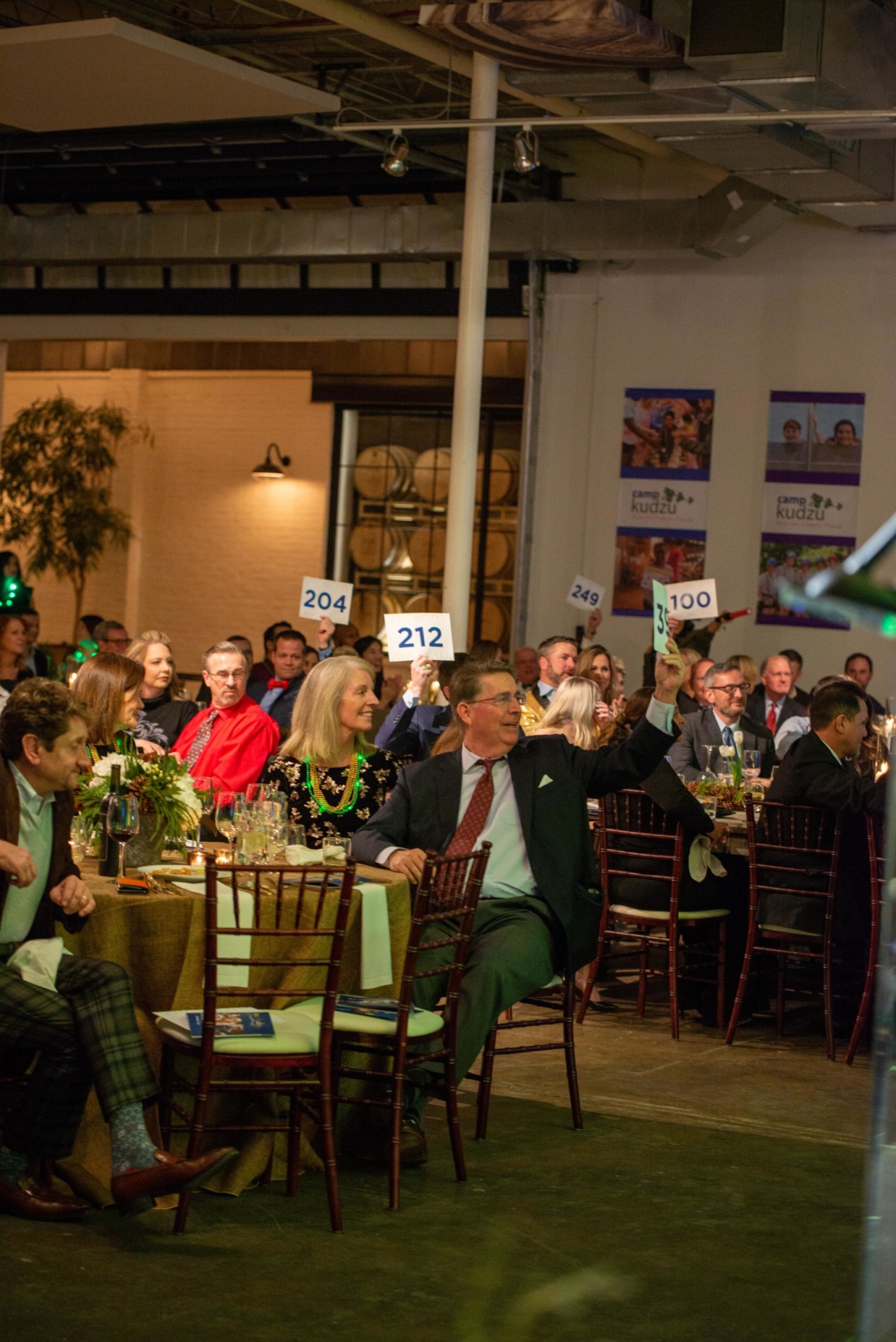 Event attendees participating in an auction at a Camp Kudzu event