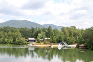 A view of the landscape of Camp Barney, including the lake in the foreground and camp buildings in the background