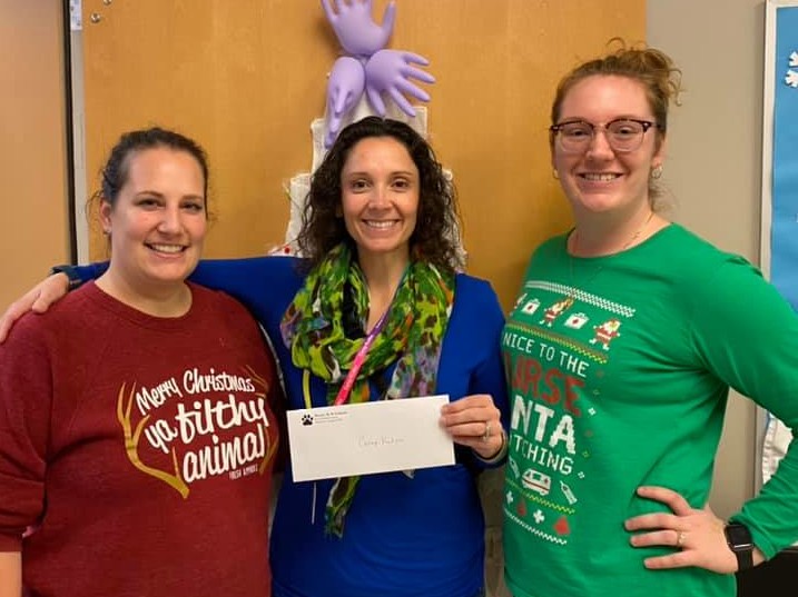 Cyndi Satlow smiles and holds a check presented by two nurses from Hesse Elementary in Savannah